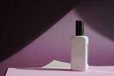 Mor arka planda bir parfüm şişesi. Minimalizm kavramı. Kağıt arkaplan. Kimlik modelleme konsepti