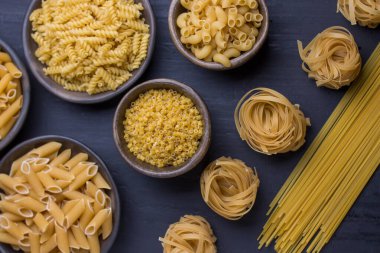 Farklı kaplarda, siyah arka planda çeşitli erişteler.