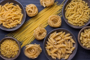 Farklı kaplarda siyah zemin üzerinde çeşitli erişteler