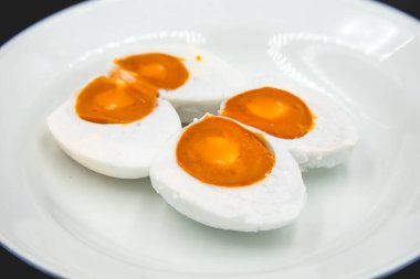 Beyaz tabakta iki tuzlanmış yumurta dilimlendi..