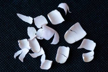 Tırnaklardan çıkarılan jel cilasının yakın çekimi, siyah arka planda kırılmış sahte akrilik tırnak parçaları..