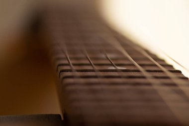 Çelik gitar tellerinin yakın çekim detayları ve müzik yapmak için perdeler. Seçici odak noktasında gitar boynu.