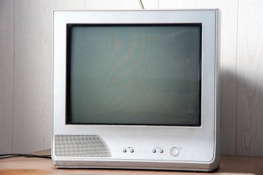 Antenli eski bir televizyon tozlu bir masanın üzerinde duruyor. Ön görünüm.