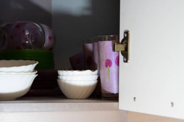 Beyaz ahşap mutfak dolabında bir sürü renkli ve temiz seramik tabak ve tabaklar güzelce raflarda yıkandı..