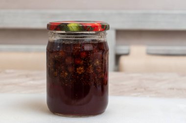 Cam kavanozda ev yapımı çilek reçeli ve masasında renkli bir kapak var. Sağlıklı beslenme kavramı, ev yemeği..