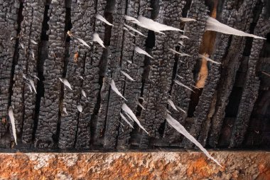 Üzerinde beyaz buz sarkıtları olan yanmış tahtalar, yakın çekim, alt manzara, ilginç bir bakış açısı..