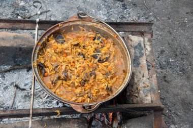 Geleneksel Polonya güveci, lahana, sosis, et ve mantarlar, ateşin üzerindeki bir kazanda olduğu kadar yakın plan.