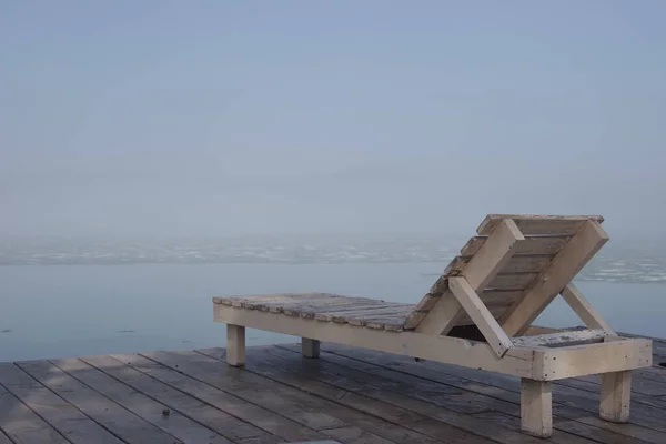 在雪融的湖边 有一张空的躺椅 周围没有人 春天的早晨 放松的概念 — 图库照片