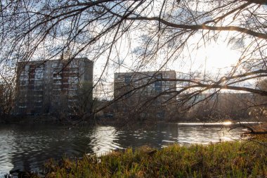 Yüksek evlerin yansımasıyla güzel bir bahar nehri. Kırık çimenler kıyıda ve kirli sahillerde alüvyonlarda.