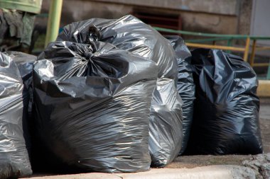 Kaldırımda temizlik için bekleyen bir yığın plastik çöp torbası..