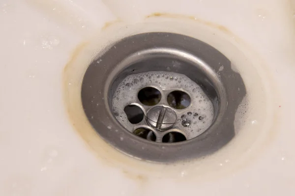 metal sink in a white bathtub, sink. Dirty drain. The concept of homework, disinfection.