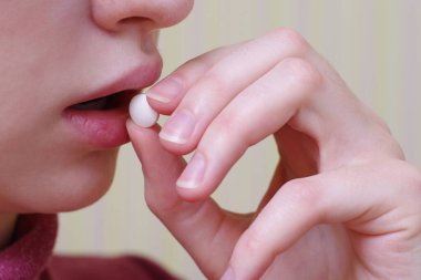 Genç kız ağzına beyaz bir hap koydu, kız ilacı yuttu. Sağlık kavramı.