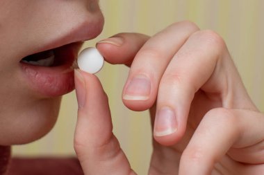 Genç kız ağzına beyaz bir hap koydu, kız ilacı yuttu. Pandemik Tedavi Konsepti, COVID19.