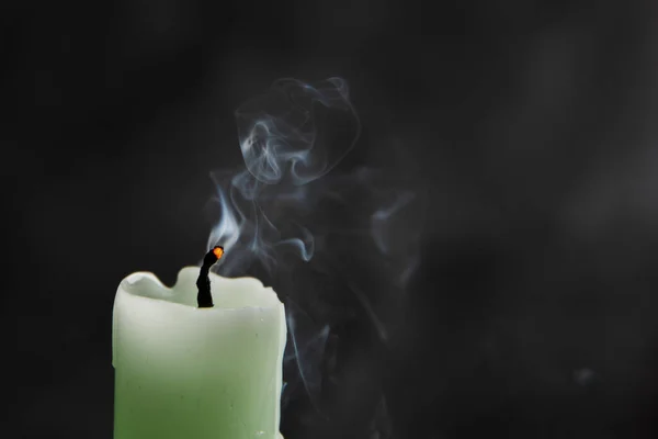 Extinct candle with smoke on a black background, symbol of death.