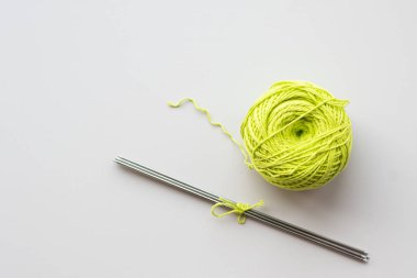 Yeşil iplikçikli glomerulinin yakın çekimi ve açık gri arkaplanda örgü iğneleri, üst görünüm, kopyalama alanı. Hobi kavramı, yaratıcılık.