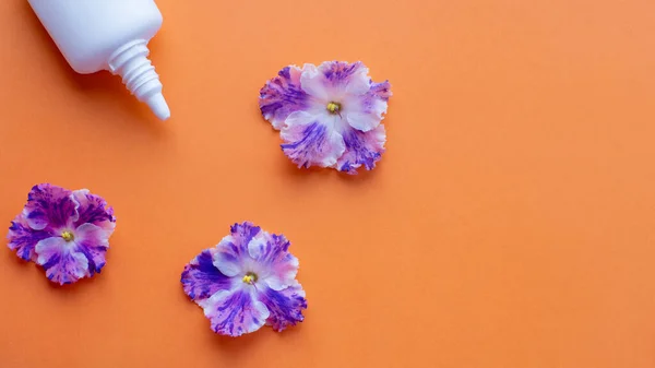 Lata Spray Branco Com Flores Violetas Fundo Laranja Deitado Plano — Fotografia de Stock