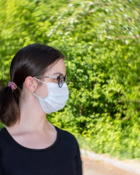 Retrato de cerca de una hermosa joven que lleva una mascarilla médica desechable en un público, epidemia de Covid-19 — Foto de Stock
