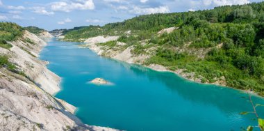 Turkuaz nehir ormanlı küçük dağların arasında. Mavi gökyüzü ve beyaz bulutlarla muhteşem bir yaz manzarası. Romantik seyahatler için cennet, sessizlik içinde rüya görmek için derin ve berrak sulara bakmak için..