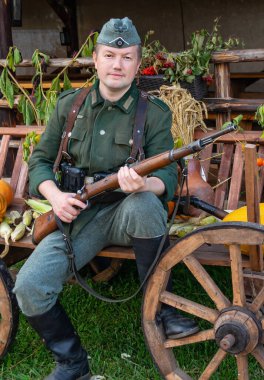 Alman piyade askeri, elinde tüfekle askeri üniforma giyiyordu. İkinci Dünya Savaşı 'nın tarihsel yeniden canlandırması. Kırsal alan. Renkli fotoğraf. Ozertso, Minsk bölgesi, Belarus