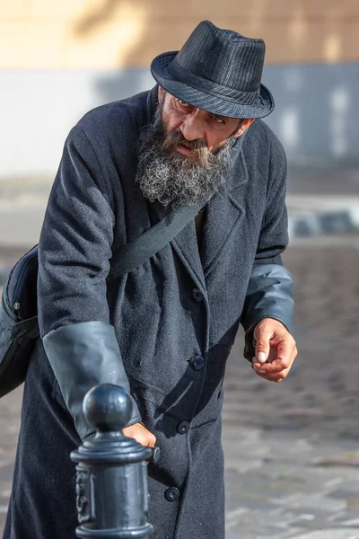 ワルシャワ ポーランド 2012年 黒の帽子と黒のコートでひげと口ひげを持つホームレスの男性は杖の助けを借りて行っています ストリートビュー 社会ドキュメンタリーの概念 選択的焦点 — ストック写真