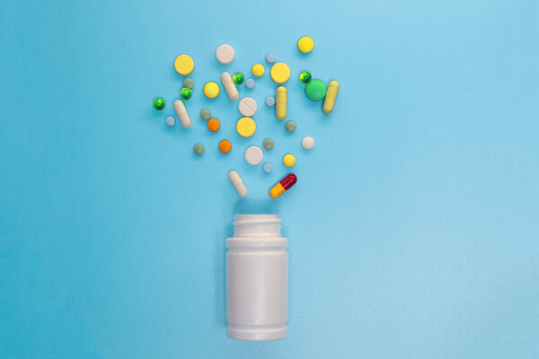 Ассорти лекарственных препаратов таблетки, таблетки и капсулы и бутылки на синем фоне. Копирование текста
