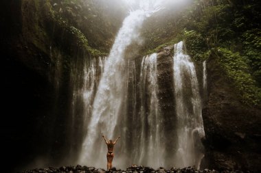 Kız Bali 'de bir ormanda muhteşem bir şelalenin tadını çıkarıyor.