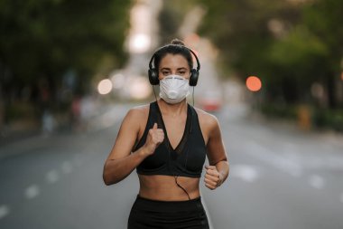 Coronavirus hapsi sırasında kız sokakta maskeyle spor yapıyor.