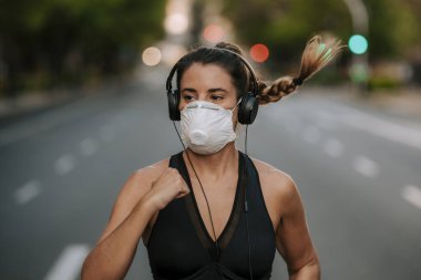 Coronavirus hapsi sırasında kız sokakta maskeyle spor yapıyor.