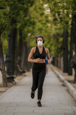 Coronavirus hapsi sırasında kız sokakta maskeyle spor yapıyor.