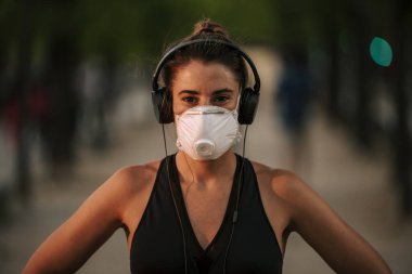 Coronavirus hapsi sırasında kız sokakta maskeyle spor yapıyor.