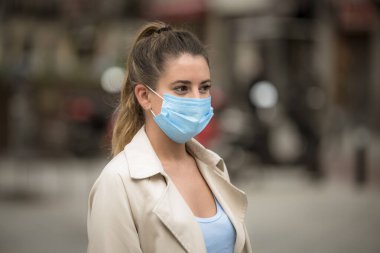Coronavirus karantinası sırasında tıbbi maskeli bir kız sokakta yürüyor.