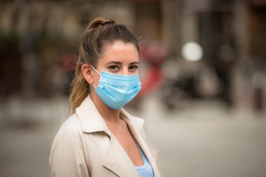 Coronavirus karantinası sırasında tıbbi maskeli bir kız sokakta yürüyor.