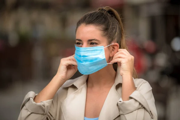 girl puts on a medical mask on the street during the coronavirus quarantine