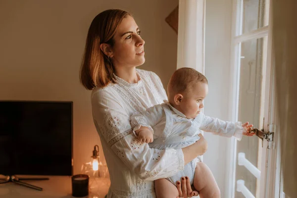 Ung Mor Tittar Genom Fönstret Med Bebis — Stockfoto