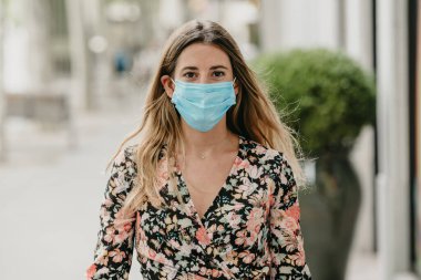 Coronavirus sırasında İspanya 'da tıbbi maskeyle yürüyen bir kız.