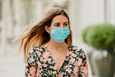 Coronavirus sırasında İspanya 'da tıbbi maskeyle yürüyen bir kız.
