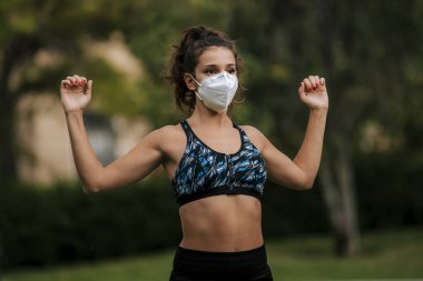 Tıbbi maske takan bir kaçakçı, Coronavirüs salgını Covid-19. Spor, karantinada aktif yaşam yüz maskesi korumalı cerrahi sterilizasyon. Corona Salgını 'nda atletizm pistinde açık hava koşusu. yoga parkı