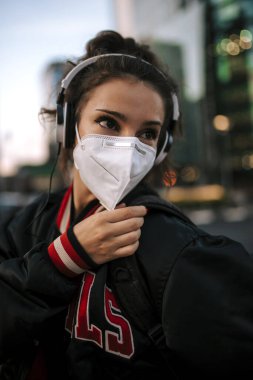 Spor giyinmiş genç bir kız İspanya 'daki şehir caddesinde tıbbi maske takıyor. Coronavirus salgını Covid-19