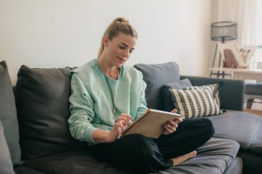 Mutlu güzel bir kadın video seyrediyor ya da evdeki kanepede oturup eğleniyor..