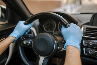 Araba kullanan bir adam salgın sırasında tıbbi maske takıyor, maskeli bir taksi şoförü, virüsten korunuyor. Beyaz arabalı bir sürücü. Koronavirüs, hastalık, enfeksiyon, karantina, covid-19