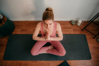 Güzel sarışın kadın evde antrenman yapıyor. Kadın evde yoga yapıyor. Sağlıklı ve aktif yaşam tarzı için egzersiz dersleri alan formda bir kız. Kadın evde çalışmak için karantina kullanıyor. Evimde geriniyorum