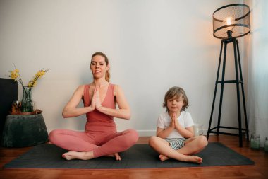 Genç anne ve oğlu evde yoga yapıyor. Sabahları çocuk egzersizi yapan sportif bir anne. Anne ve oğlu egzersizleri birlikte yapıyor, sağlıklı bir aile hayatı. Coronavirus evde kal. COVID-19 tarafından acil kapatma.