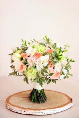 Masada bir buket nane ve şeftali rengi var. Beyaz frezya, yeşil dianthus, şeftali gülleri, hafif kasımpatı ve taze yeşilliklerden oluşur. Gelin ya da kız için buket. 