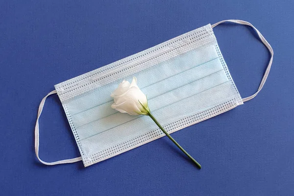 Λευκό Λουλούδι Βρίσκεται Μια Ιατρική Μάσκα Μπλε Φόντο Έννοια Της — Φωτογραφία Αρχείου