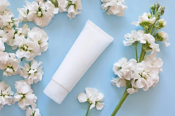 beauty spa medical skincare and cosmetic lotion bottle cream packaging product on on a pale blue background with white flowers. Overhead view. Floral flat lay, life style. Clean beauty concept