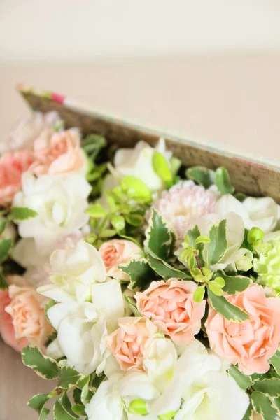 Flower box with white freesia, peach roses, light greens. Fluffy, floral birthday present or other celebration.