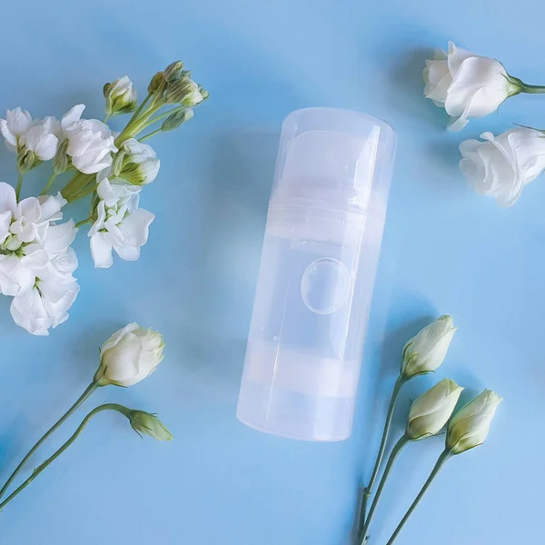 Şeffaf kayganlaştırıcı jel şişesinin taklidini yap. Beyaz çiçekli mavi arka plan. Samimi masaj, rahat seks. Yaşam tarzı, düz yatış..