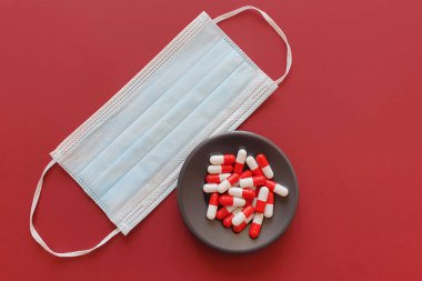 İlaçlar ve tıbbi maske kırmızı arka planda. Sağlık Konseptini Korumak
