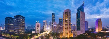 Jakarta 'nın merkez iş bölgesinin alacakaranlıktaki hava manzarası (mavi saat). Jakarta şehir manzarası gün batımında. Üç fotoğraftan bir panorama dikilmiş. Jakarta şehir manzarası. Geniş ekran fotoğrafı.