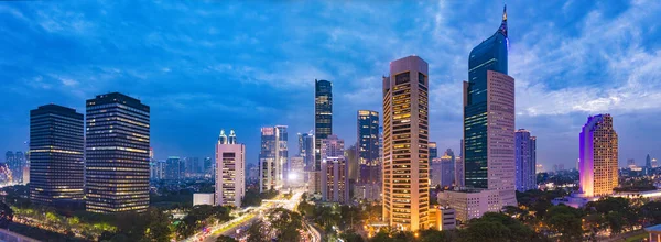 Jakarta 'nın merkez iş bölgesinin alacakaranlıktaki hava manzarası (mavi saat). Jakarta şehir manzarası gün batımında. Üç fotoğraftan bir panorama dikilmiş. Jakarta şehir manzarası. Geniş ekran fotoğrafı.